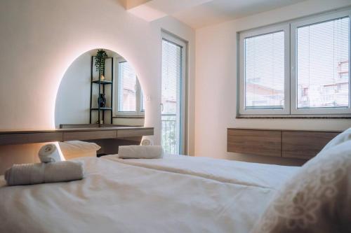 een slaapkamer met 2 bedden en een spiegel en ramen bij The White Lotus Apartment in Ohrid