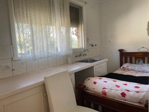 a kitchen with a sink and a bed with a window at D High quality large bed rooms near commercial areas, universities, and rail transit in villas in Melbourne