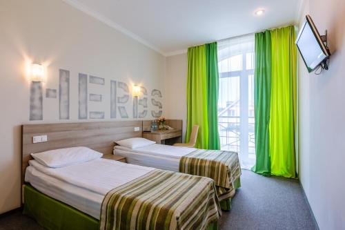 two beds in a hotel room with green curtains at PracticOtel in Kyiv