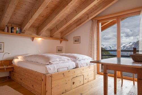a bedroom with a bed and a table and a window at Papillon in Bettmeralp