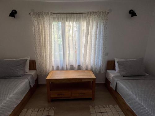 a room with two beds and a table and a window at Miracle Houses Къщи за гости Чудеса in Varshets