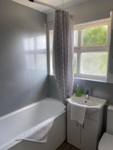 a bathroom with a sink and a bath tub and a window at House number 4 Sleeps up to 5 with Smart TVs in every room in Wellington