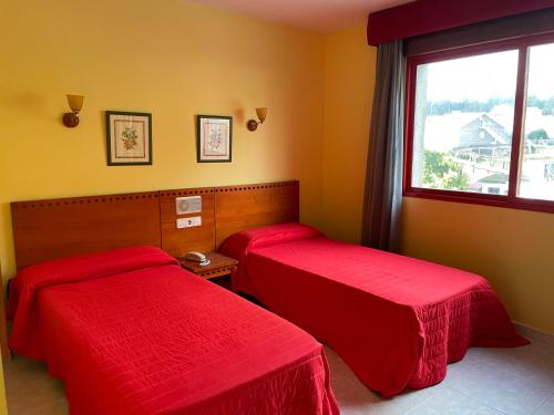 2 camas rojas en una habitación con ventana en Hotel Acquamaris 3000, en Sanxenxo