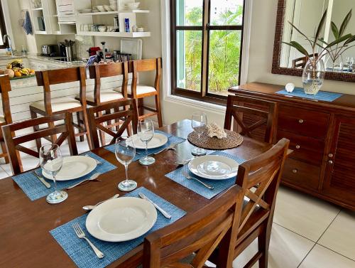 a dining room table with plates and wine glasses at Eden Island (GIE Apartment) in Eden Island