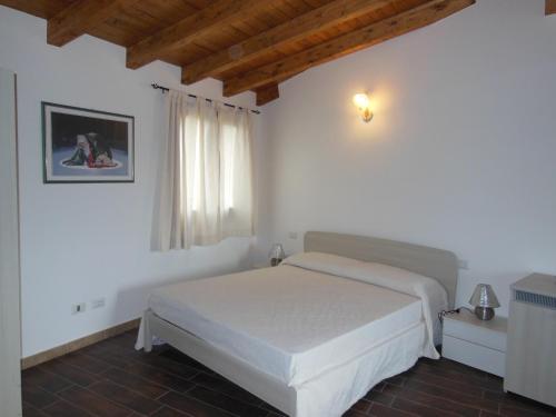 a bedroom with a white bed and a window at B&B Pettirosso in San Teodoro
