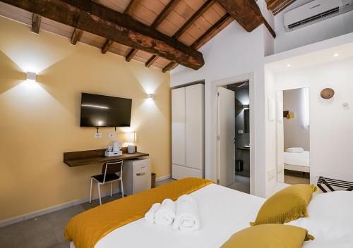 1 dormitorio con 2 camas, escritorio y TV en Ad Oriente, en La Maddalena
