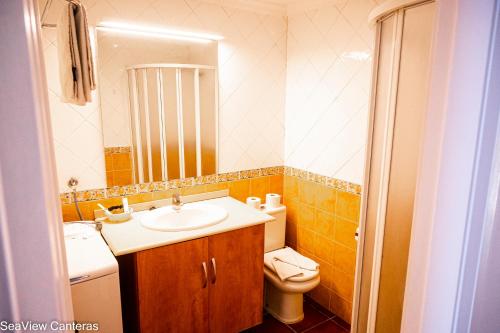 a bathroom with a sink and a toilet and a mirror at Seaview Canteras in Las Palmas de Gran Canaria