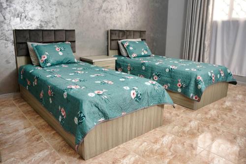 sypialnia z 2 łóżkami z zielonymi kołdrami w obiekcie Treasure of Petra w mieście Wadi Musa