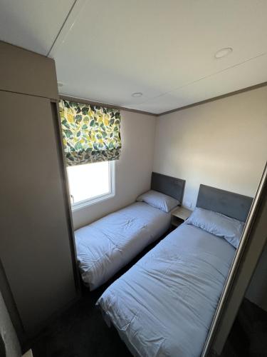 two beds in a small room with a window at Lake View 92 in Millom