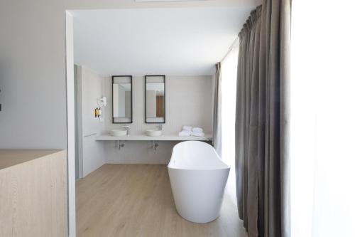 a white bathroom with a sink and a mirror at Hotel H4 Cangas 3 Superior in Cangas de Morrazo