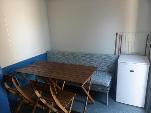 a wooden table and two chairs and a refrigerator at Parque de Campismo Orbitur Evora in Évora
