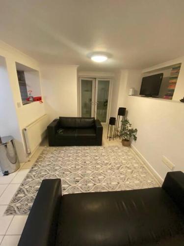 - un salon avec deux canapés noirs et un tapis dans l'établissement Gravesend 1 Bedroom Flat 2 Min Walk to Station & Town Centre - longer stays available, à Kent