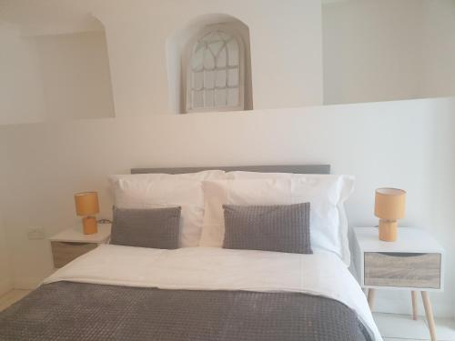 um quarto com uma cama com lençóis brancos e almofadas em Gravesend 1 Bedroom Flat 2 Min Walk to Station & Town Centre - longer stays available em Kent