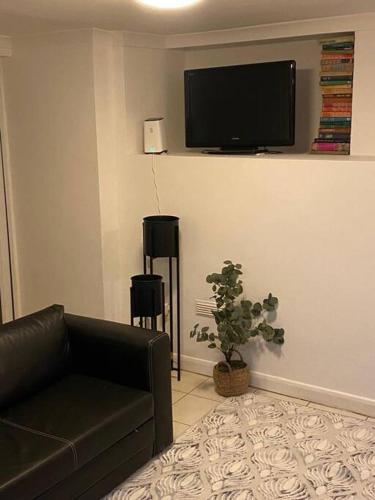 uma sala de estar com um sofá e uma televisão na parede em Gravesend 1 Bedroom Flat 2 Min Walk to Station & Town Centre - longer stays available em Kent