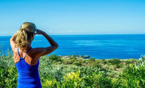 a woman in a blue dress looking at the ocean at Bio Guesthouse Mani Sonnenlink in Pírgos