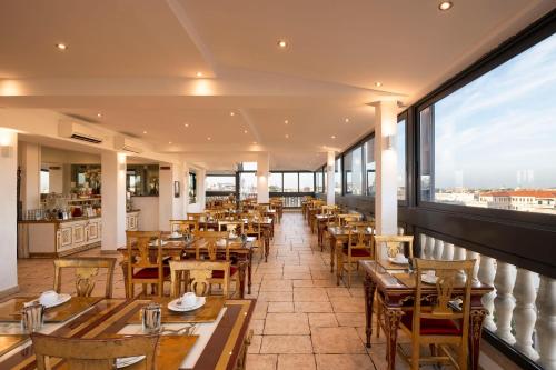 een restaurant met tafels en stoelen en een groot raam bij Romanico Palace Luxury Hotel & SPA in Rome