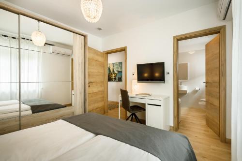 een slaapkamer met een bed, een bureau en een televisie bij Casa Maya Deluxe Appartment with a pool in Opatija