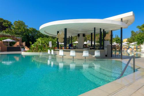 a swimming pool with white chairs and a building at Olympic Palace Hotel in Ixia