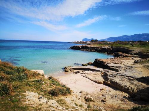 una spiaggia con rocce e l'oceano in una giornata di sole di Torre Pozzillo Beach a Cinisi