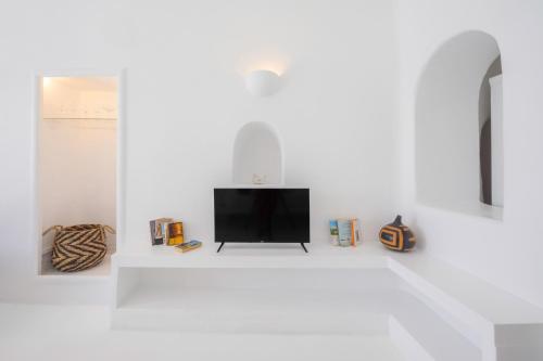 a living room with a tv on a white wall at Sophia Oia View in Oia