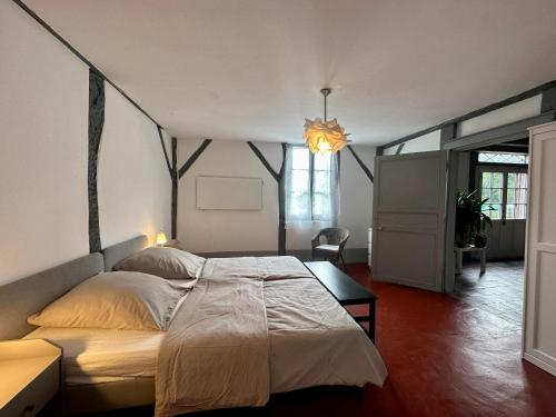 a bedroom with a large bed and a chandelier at Maison Magnolia in Onesse-et-Laharie