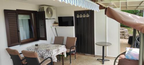 eine Terrasse mit einem Tisch und Stühlen sowie einem TV in der Unterkunft Apartments Svjeta in Jadranovo