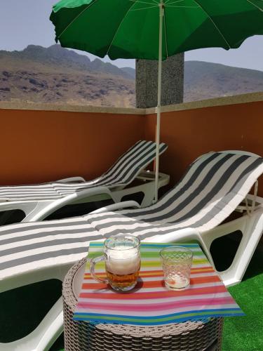 a table with a green umbrella and two chairs at THE HAPPINESS PENTHOUSE Dream Holiday at 100m Beach! in Candelaria