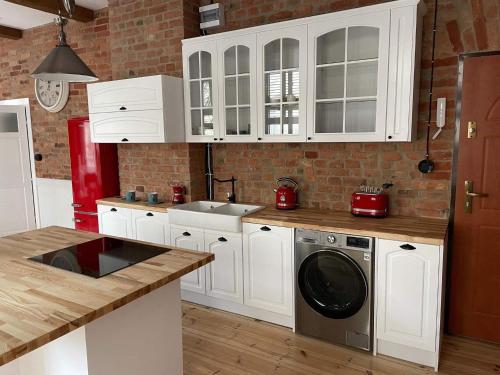 a kitchen with white cabinets and a washing machine at Apartments PSD - Filmowa in Słupsk