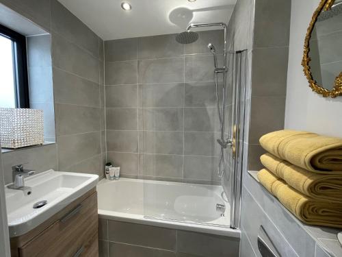 ein Bad mit einer Badewanne, einem Waschbecken und einer Dusche in der Unterkunft Salt Yard Cottage No 3 in Whitstable