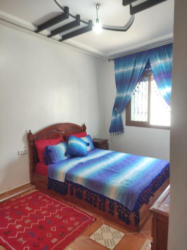 a bedroom with a bed with blue and red pillows at Rabia ahayek in Chefchaouen