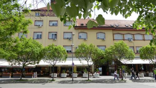 een groot geel gebouw met bomen ervoor bij Hotel Zepter Palace in Banja Luka
