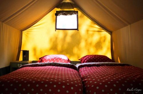 deux lits dans une tente à pois rouges et blancs dans l'établissement TENTE ECUREUIL 2 PERSONNES (CAMPING LOU CANTOU CEVENOL), à Anduze