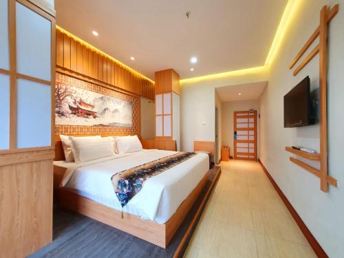 a bedroom with a large bed and a flat screen tv at Little Tokyo in Yogyakarta