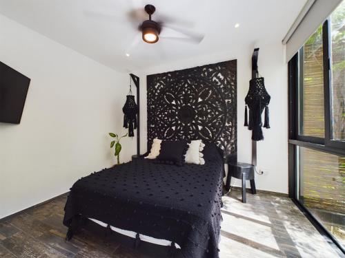 a bedroom with a black bed and a ceiling fan at Casa Kuaan Mani TH 1 in Tulum