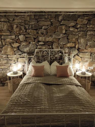 Cama en habitación con pared de piedra en Szomolyai Vadvirág vendégház en Szomolya