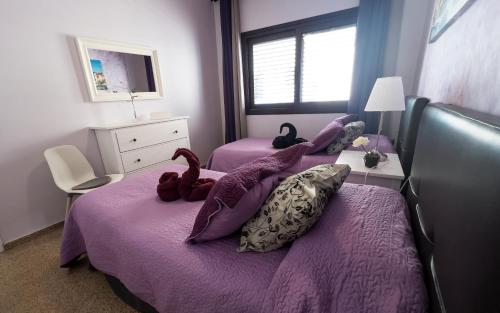 a bedroom with two purple beds with stuffed animals on them at Apartamentos Mesa in Valle Gran Rey