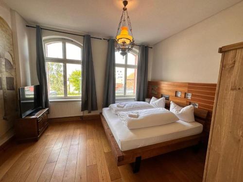 a bedroom with a bed and a tv and windows at Pension Stellwerk Ilsenburg in Ilsenburg