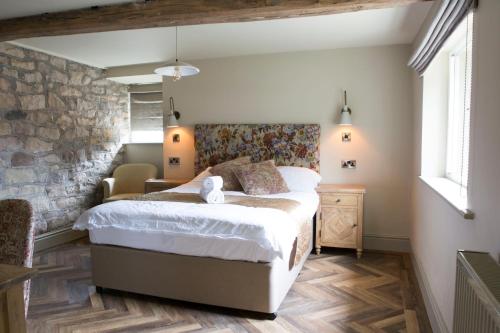 - une chambre avec un lit et un mur en pierre dans l'établissement Square & Compass, à Two Dales