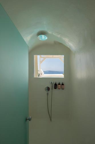 a bathroom with a shower with a window at Sophia Oia View in Oia