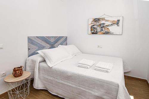 a white bedroom with a bed with two towels on it at Nautilus 3 - Elegante Apartamento para 6 con Piscina, Wifi y AC en Rota in Rota