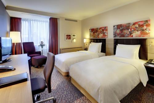 a hotel room with two beds and a desk at Hilton Mainz in Mainz