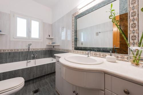 a bathroom with a sink and a toilet and a mirror at Sun and Salt 3bedroom House in Aliki