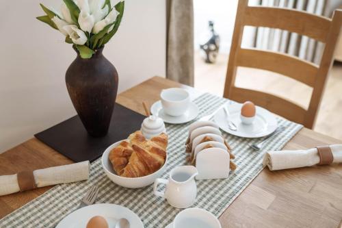 una mesa con huevos y pan y un jarrón de flores en Tredenwith House en St Just