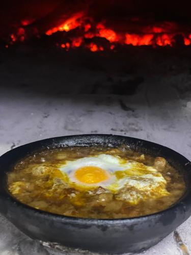 a frying pan with an egg in front of a fire at VILA DISHA in Tirana