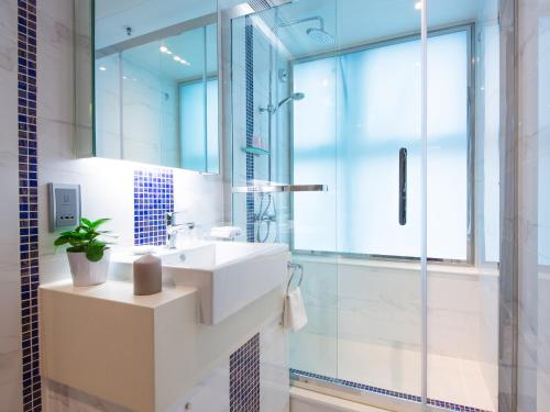 a bathroom with a white sink and a shower at The Bauhinia Hotel - Tsim Sha Tsui in Hong Kong