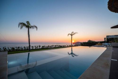 a pool with a view of the ocean at sunset at Cielo e Mare Villas in Falasarna