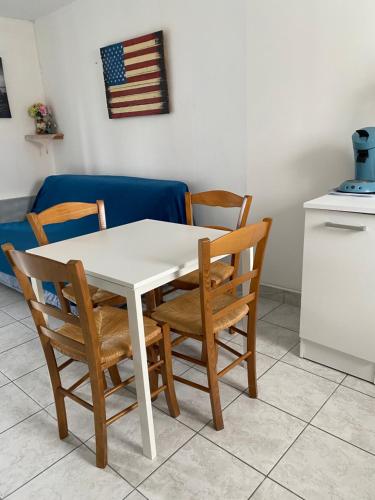 a white table with chairs and an american flag on the wall at Appartement 1 chambre et cuisine VIERVILLE-SUR-MER,plage du Débarquement in Vierville-sur-Mer