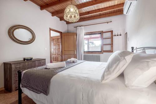 una camera da letto con un grande letto bianco e uno specchio di Alice Cottage in Viros Village a Virós