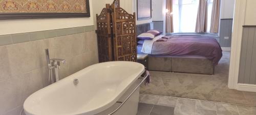 ein Badezimmer mit einer Badewanne neben einem Bett in der Unterkunft Rooms by Maes y mor Town Centre in Aberystwyth