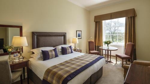 LonghorsleyにあるMacdonald Linden Hall Hotel, Golf & Spaのベッド、デスク、窓が備わるホテルルームです。